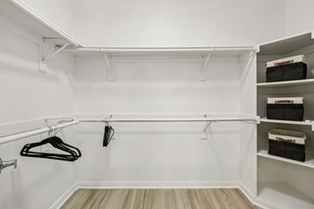 A white closet with clothes hanging and shelves.